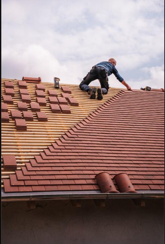 Roofer laying tiles on a pitched roof